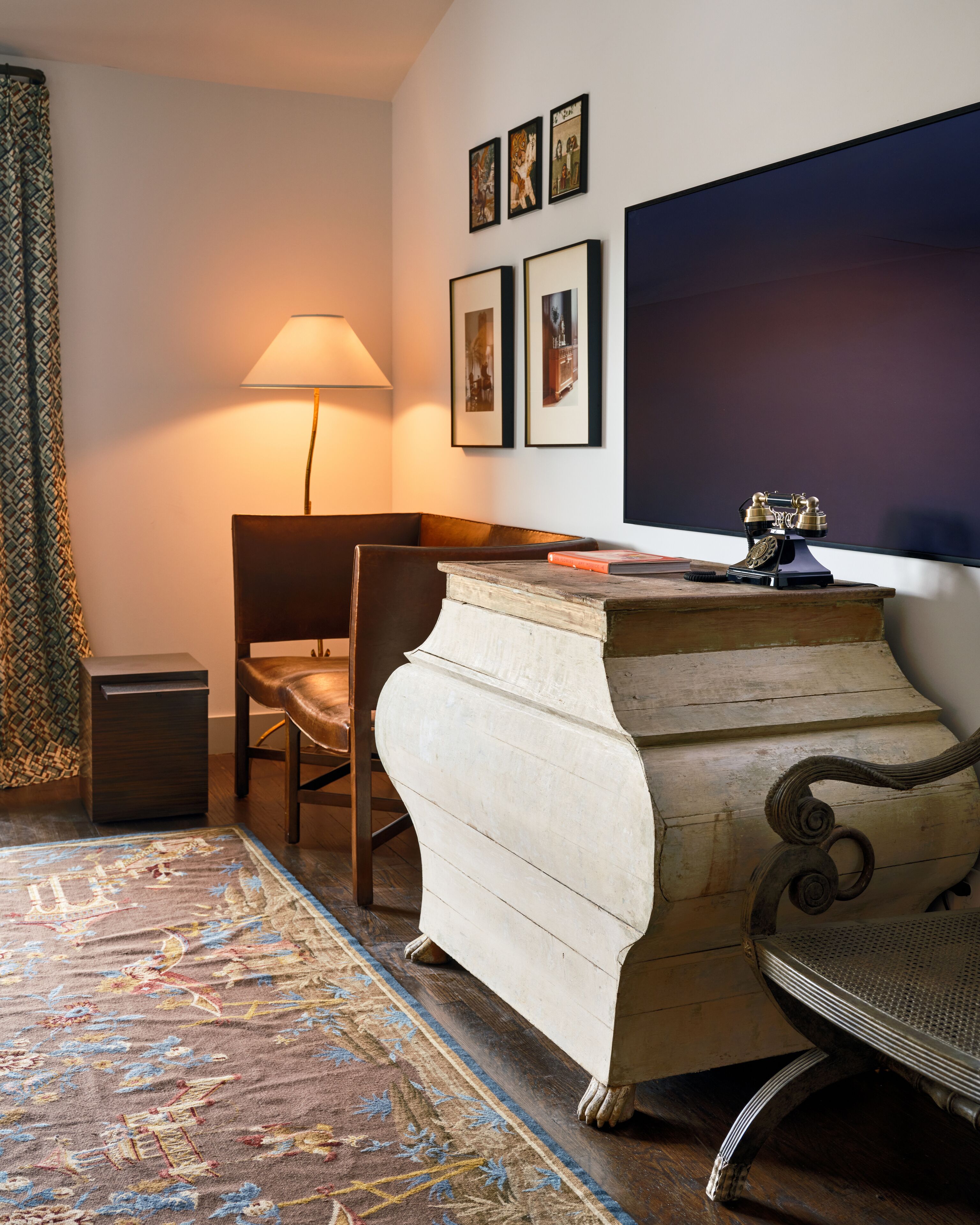 A room with a wooden desk, a chair, a lamp, and a patterned rug.