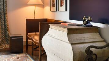 A room with a wooden desk, a chair, a lamp, and a patterned rug.