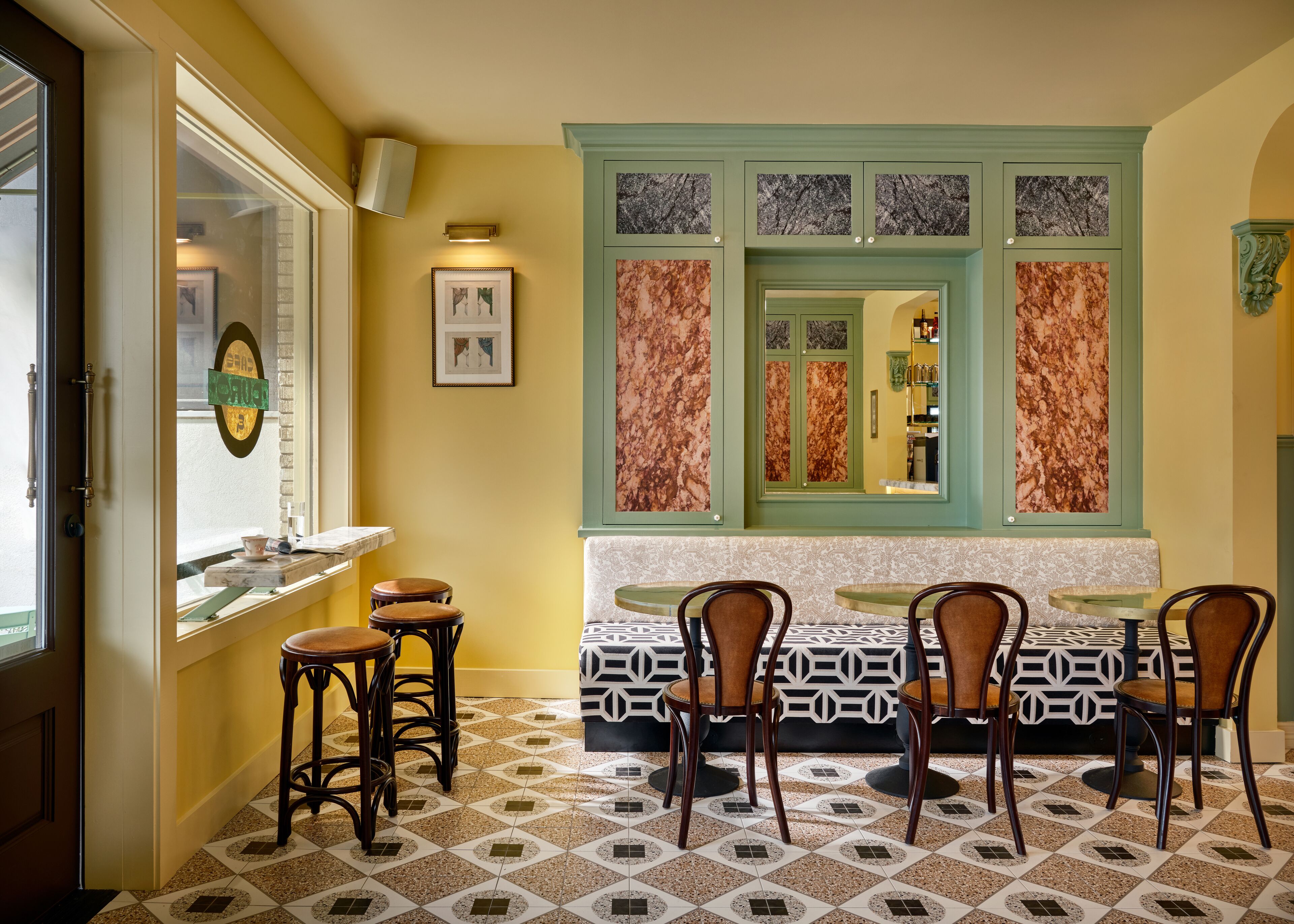 Una zona de menjador amb un paviment estampat, una paret d'accent verd i obres d'art emmarcades.
