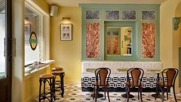 Una zona de menjador amb un paviment estampat, una paret d'accent verd i obres d'art emmarcades.