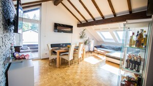 Ein moderner Wohnbereich mit Holzboden, einem Essbereich mit Tisch und Stühlen, einer Couch und einer Glasvitrine mit Flaschen.