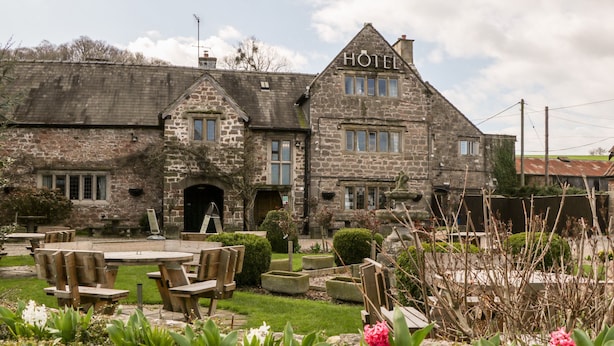 A stone building with a sign reading "HOTEL" and a garden with outdoor seating. - Steel Works Farm (Ross-on-Wye)