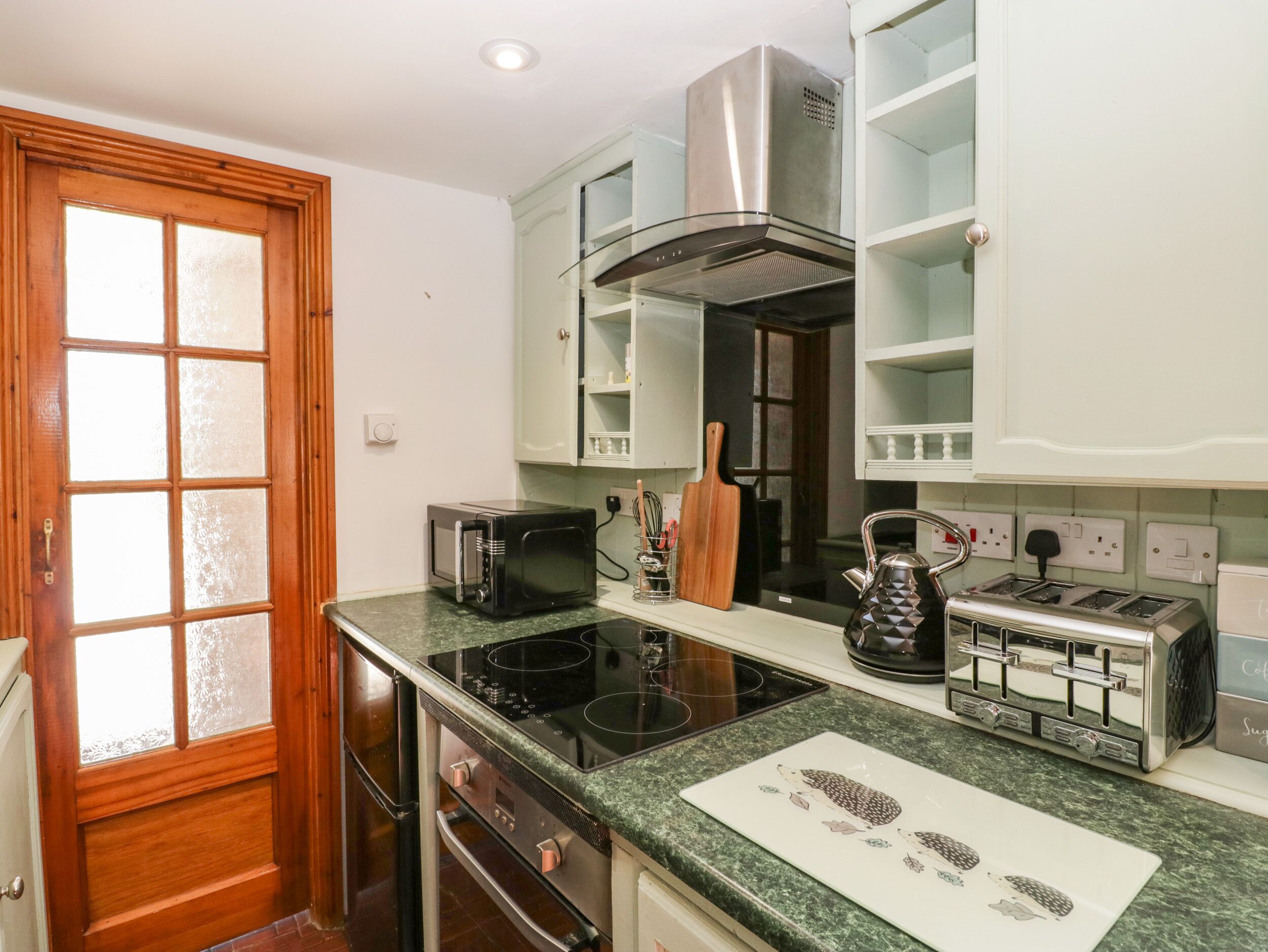 A compact kitchen with a stove, microwave, toaster, and a coffee maker.