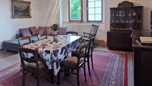 Un comedor con una mesa preparada para cuatro personas, rodeada de sillas, un tapete estampado y una araña.