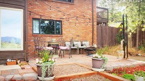 A patio with outdoor furniture, a brick wall, and potted plants. - Cabin's entire, private lower level w/ mountain view & cozy, comfortable living. (Colorado Springs)
