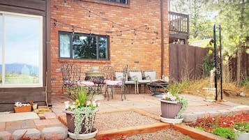A patio with outdoor furniture, a brick wall, and potted plants.