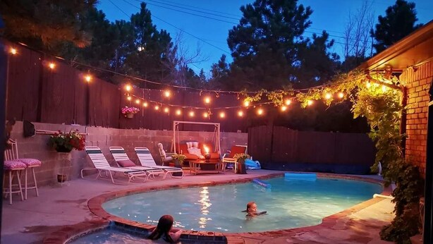 A backyard with a swimming pool, lounge chairs, and string lights. - Cabin's entire, private lower level w/ mountain view & cozy, comfortable living. (Colorado Springs)