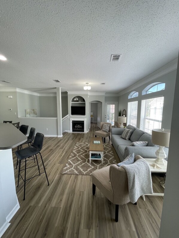 A spacious living area with a fireplace, a dining area with chairs, a sofa, and a lamp.