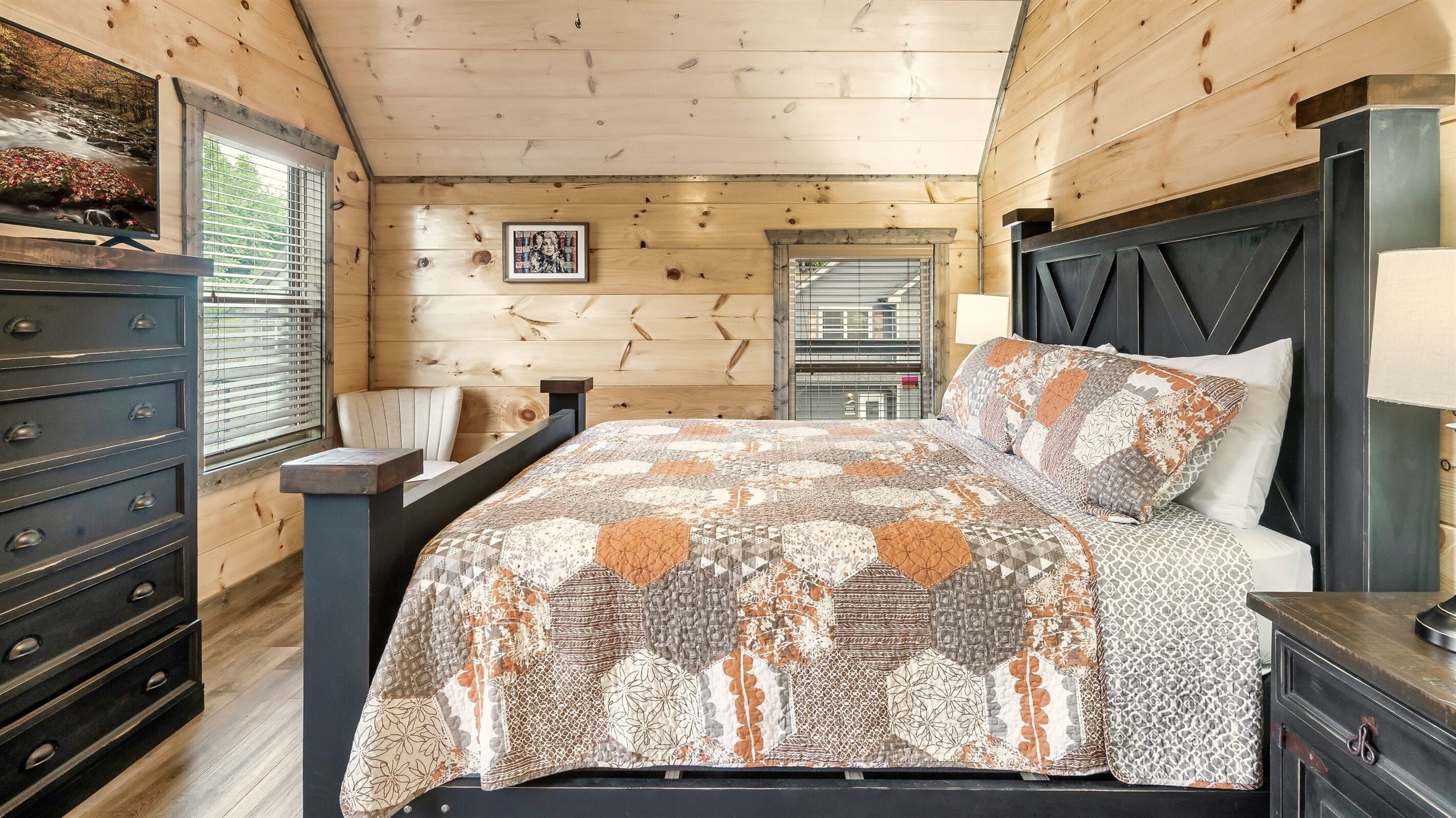 A wooden-paneled bedroom with a bed, dresser, and a window with blinds.