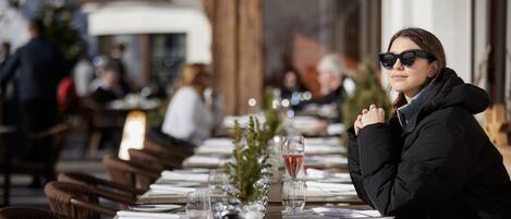 Un restaurante con mesas y sillas de madera, un árbol de Navidad y una copa de vino sobre la mesa.