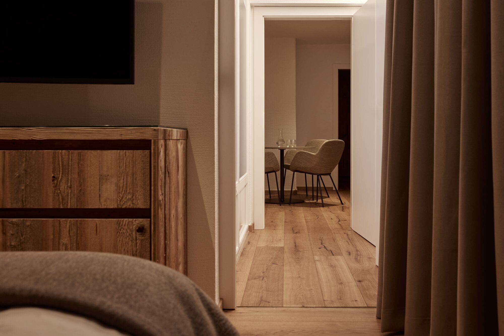 Un couloir étroit mène à une salle à manger où se trouvent une table et des chaises.