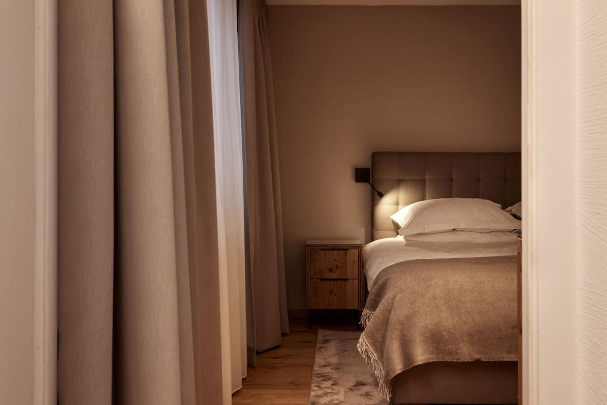 Un dormitorio con cama, mesita de noche y una lámpara de pared.