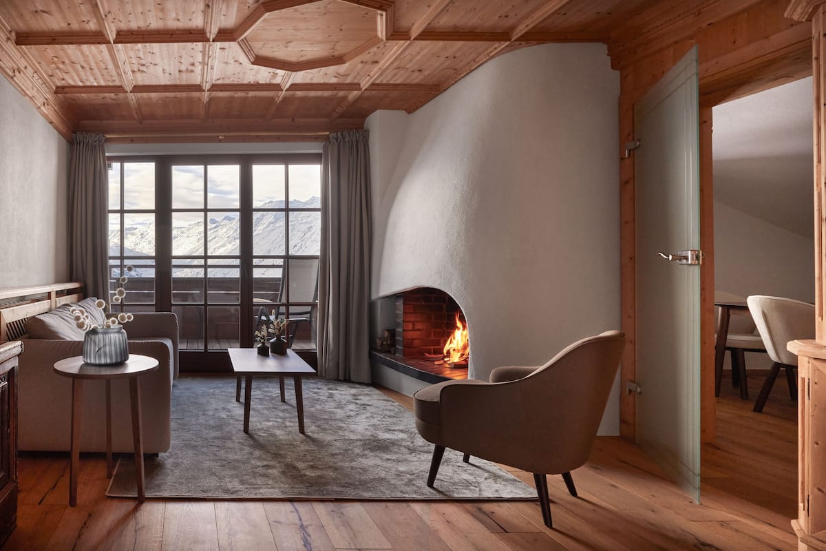 Una sala de estar acogedora con chimenea, techo de madera y vistas a montañas a través de amplios ventanales.