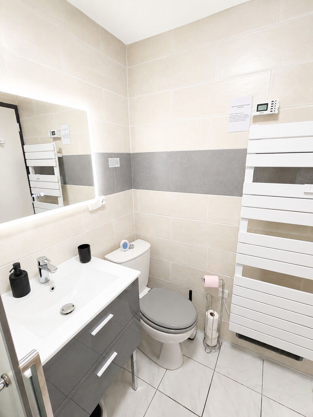 Ein modernes Badezimmer mit Toilette, Waschbecken und Spiegel.