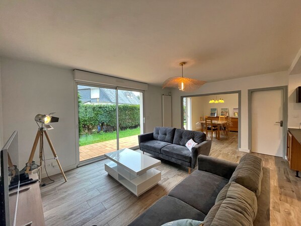 A modern living room with a grey sofa, a white coffee table, and a tripod-mounted projector. - House located in a quiet area, close to the town center. (Guidel)