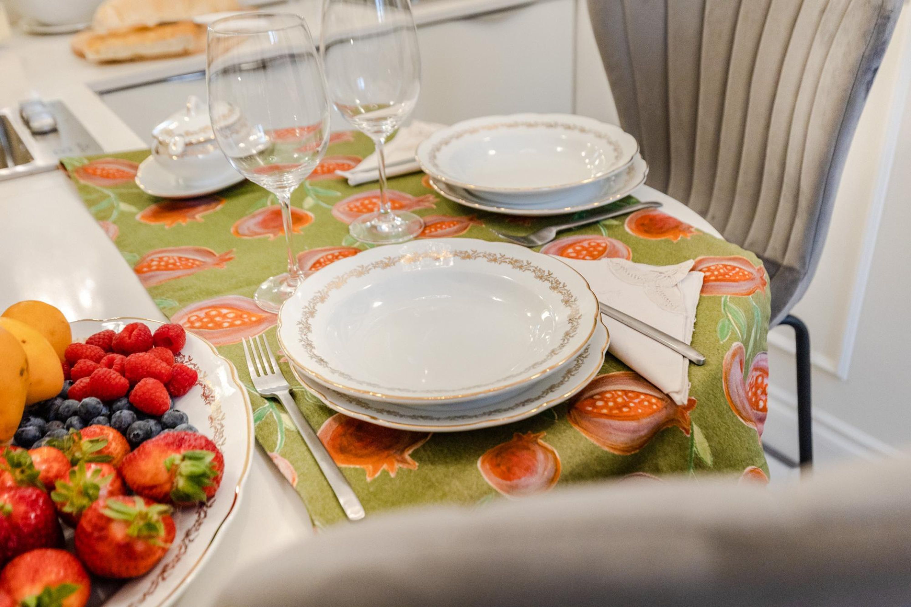 A dining table set with plates, cutlery, and a fruit platter.