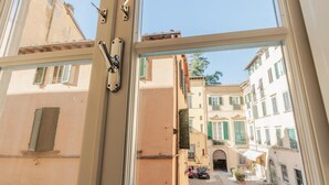 A narrow street with buildings on either side, a clear sky, and a view through an open window. - The Silk Thread the Luxury 3 Bedrooms Apartment (Lucca)