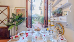 Une table mise pour un repas, avec des assiettes, des tasses et un saladier de fruits.