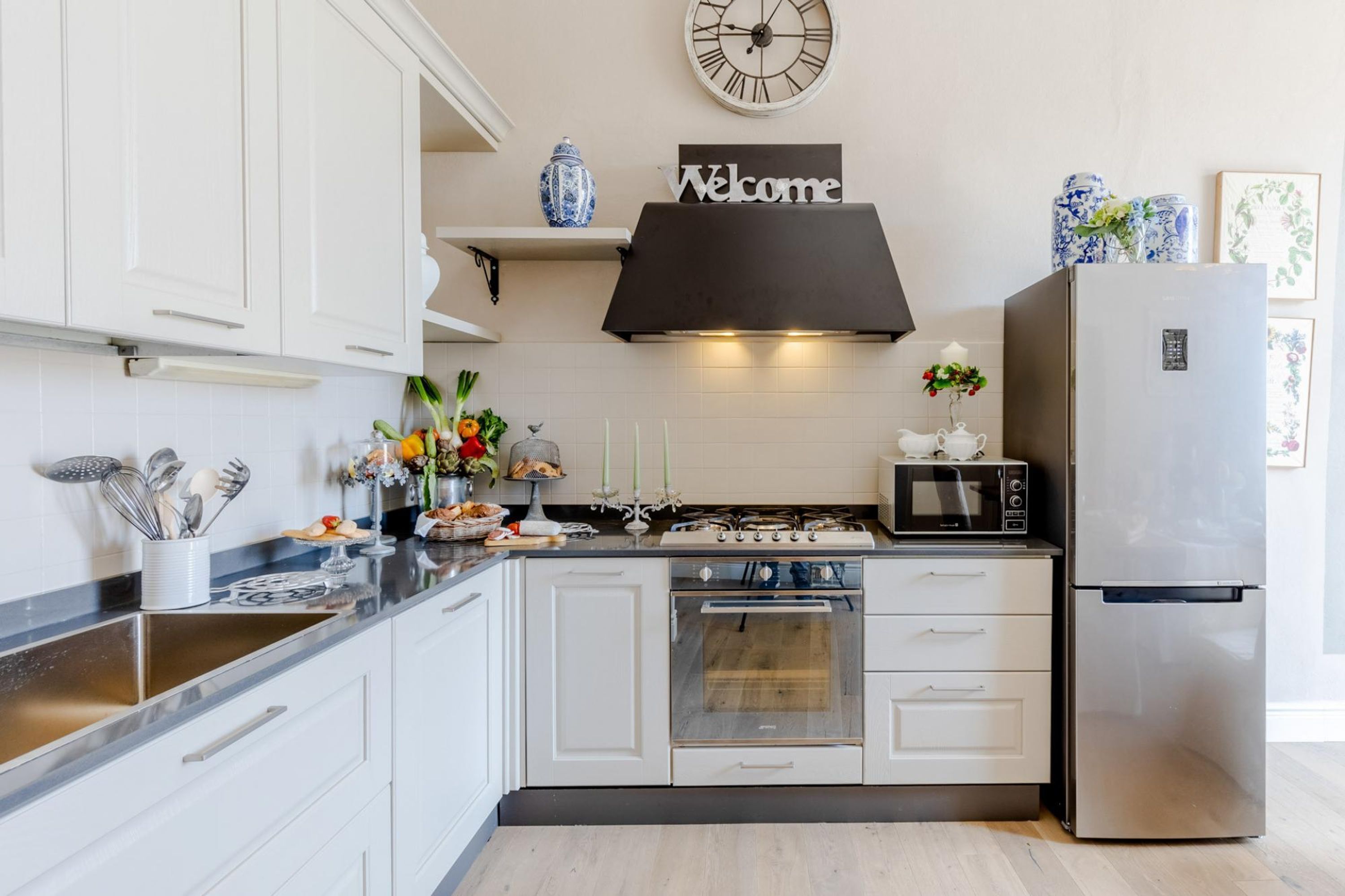 A modern kitchen with white cabinets, a stainless steel refrigerator, a microwave, and a gas stove.