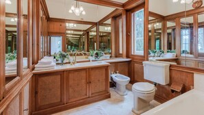 Un baño amplio con muebles de madera, un espejo grande y una bañera.