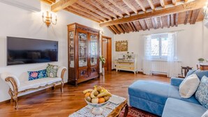 A living room with a wooden ceiling, a large flat-screen TV, a blue sofa, a white sofa, and a wooden cabinet. - Casa La Guardia a 3 Bedrooms Panoramic Apartment (Lucca)