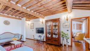 A spacious living room with wooden beams, a large cabinet, and a television. - Casa La Guardia a 3 Bedrooms Panoramic Apartment (Lucca)