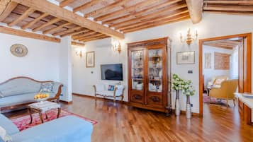 Un salón amplio con vigas de madera, un armario grande y un televisor.