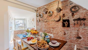 Un comedor con pared de ladrillo, una mesa de madera dispuesta con platos, tazones y diversos alimentos.
