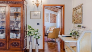 A room with a wooden cabinet, two vases with flowers, a chandelier, and a painting on the wall. - Casa La Guardia a 3 Bedrooms Panoramic Apartment (Lucca)