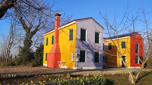 Una casa colorida de dos pisos con chimenea, rodeada por un jardín de narcisos.
