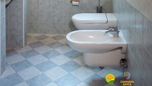 Un baño con ventana, inodoro, bidé y lavamanos.