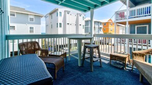A covered outdoor seating area with wicker furniture and a table, overlooking a residential neighborhood. - 🌊 Lake 'N Sea: Ocean and Lake Views | Prime Location | 1 Min Walk to Beach 🌊 (Carolina Beach)