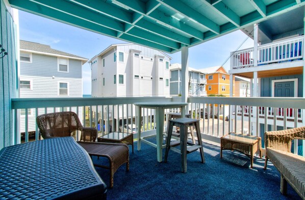 Un espacio al aire libre cubierto con muebles de mimbre y una mesa, con vista a un barrio residencial.