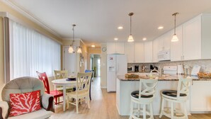 A modern kitchen with white cabinets, a central island with bar stools, and pendant lighting. - 🌊 Lake 'N Sea: Ocean and Lake Views | Prime Location | 1 Min Walk to Beach 🌊 (Carolina Beach)