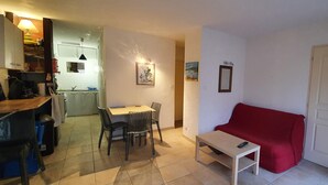 Un espace de vie compact comprenant un coin repas, un canapé rouge et une petite table.