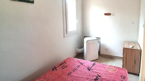 Une petite pièce, peu meublée, avec un lit, un radiateur et une armoire en bois.