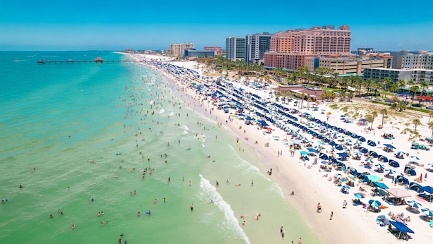 A beachside hotel with a long stretch of beach, numerous umbrellas, and a pier extending into the ocean. - $189 30 Steps from Beach l 3min Rest/Shops (Clearwater Beach)