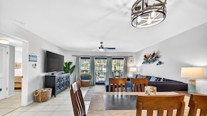A spacious living area with a dining table, chairs, a sofa, and a television. - $189 30 Steps from Beach l 3min Rest/Shops (Clearwater Beach)