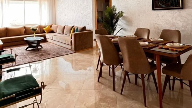 Ein geräumiges Wohnzimmer mit großzügigem Sofa, einem Essbereich mit Tisch und Stühlen sowie einer modernen Pendelleuchte.