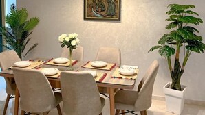 Ein Essbereich mit einem Tisch für vier Personen, einem Bild an der Wand und einer Topfpflanze.