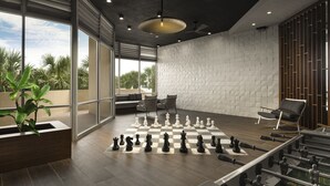 A spacious room with a large chessboard, seating area, and a view of palm trees.