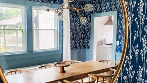 Une salle à manger avec une grande table en bois, des chaises et un grand miroir rond accroché au mur.