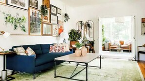 Un salon avec un canapé bleu, une table basse et divers tableaux encadrés accrochés au mur.