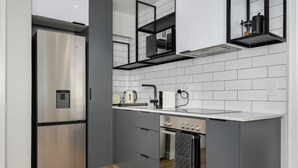 A modern kitchen with grey cabinets, a stainless steel refrigerator, a built-in oven, and a white countertop. - Point Break Studio | Groundfloor (Cape Town)