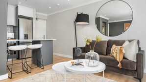 A modern living area with a sofa, coffee table, and bar stools. - Point Break Studio | Groundfloor (Cape Town)