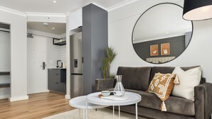 A modern living room with a grey sofa, a white coffee table, and a large round mirror on the wall. - Point Break | Studio | Kitchenette | Groundfloor (Cape Town)