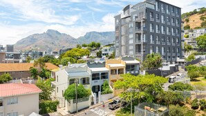 A residential area with modern buildings, a street, and a mountain in the background. - Point Break | Ground Studio | Private Courtyard (Cape Town)