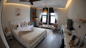 A modern bedroom with a large bed, a ceiling fan, a TV, and a desk with a chair. - AFİLLİ KÖŞK (Amasya)