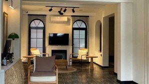 A spacious living room with a fireplace, two armchairs, a television, and a chandelier. - AFİLLİ KÖŞK (Amasya)