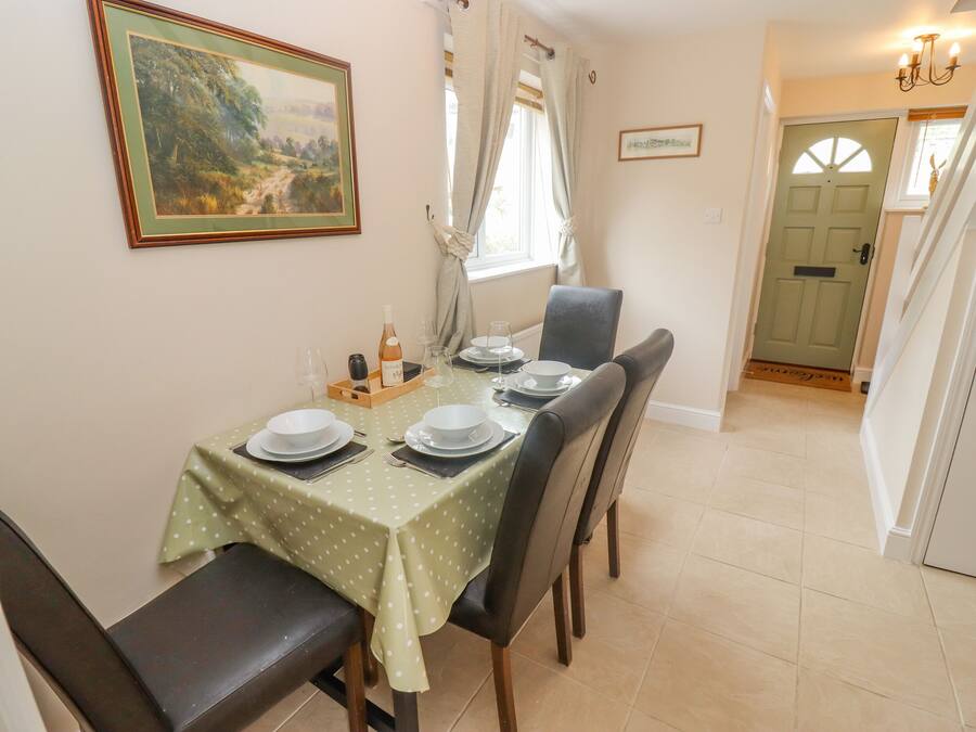 A dining area with a table set for four, including plates, glasses, and a bottle of wine.